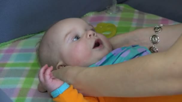 Рука матери застегивает голубые нагрудники для малыша. 4K — стоковое видео