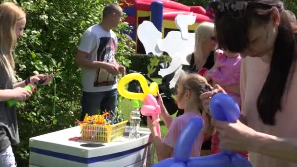Children flock to balloon sellers stall in park — Stock Video