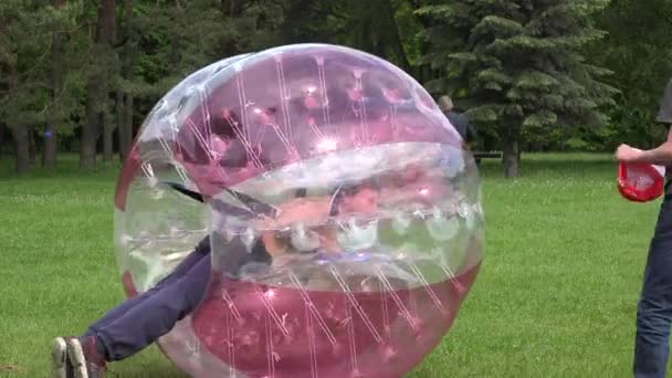 I bambini cavalcano su grande bolla colorata gonfiabile sul prato — Video Stock