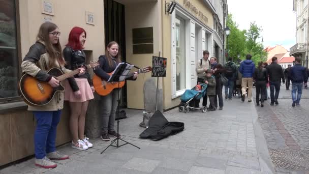 Три студентки играют на гитаре и поют. 4K — стоковое видео