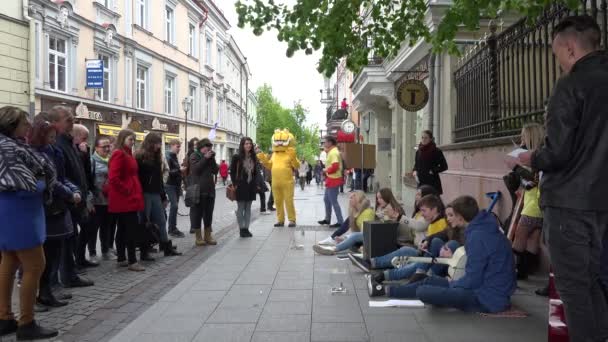 Los jóvenes se sientan en el piso de la calle y cantan. 4K — Vídeos de Stock