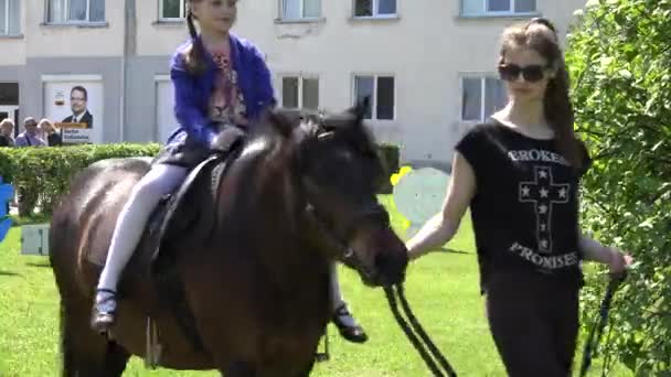 Niños montan a caballo con manipuladores en el parque verde — Vídeos de Stock