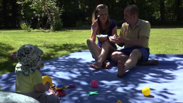 Familia feliz comer helado en cuadros y bebé lindo míralos. 4K — Vídeo de stock