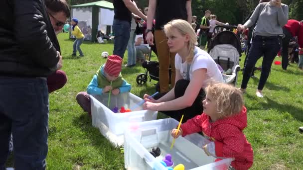 Kinderen spelen Blow plastic eenden in een klein water zwembad met stro. 4k — Stockvideo