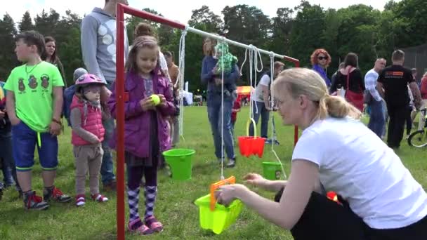 Молодая девушка бросает мяч в маленькое ведро игрушки висит на веревке. 4K — стоковое видео
