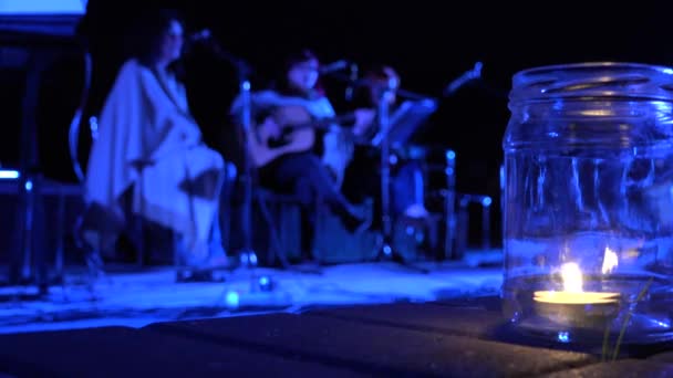 Queimadura de vela e senhoras de meia-idade tocam guitarra e cantam poesia à noite. 4K — Vídeo de Stock