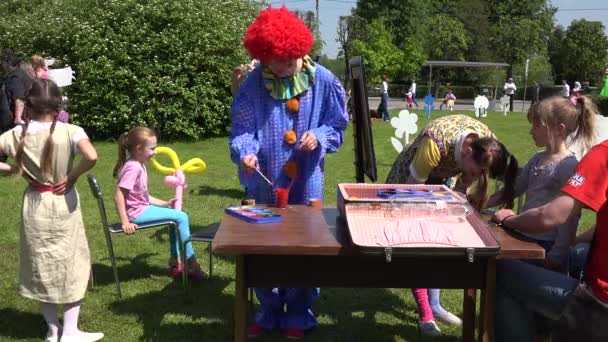 Mujer en traje colorido pintar caras y manos de niños. 4K — Vídeos de Stock