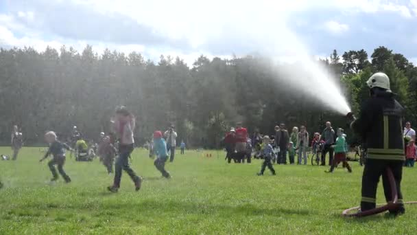 Happy kids refresh under water from firefighter man fire hose 4K — Stock Video