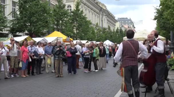 Chicos de la banda folclórica con instrumentos musicales juegan para los visitantes de la feria. 4K — Vídeo de stock