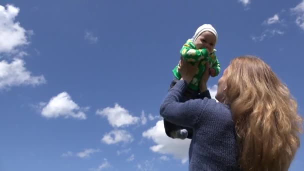 Mother throw little baby girl into air on blue sky background. 4K — Stock Video