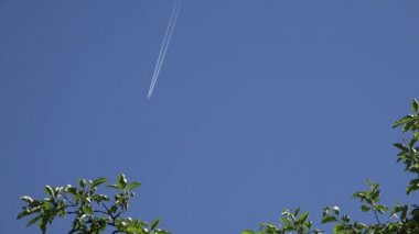 Geride bırakarak beyaz çizgiler iz mavi gökyüzünde uçak uçan. 4k