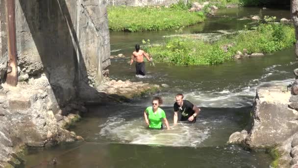 Frau und Mann waten durch Flusslauf und muskulösen Ninja. 4k — Stockvideo