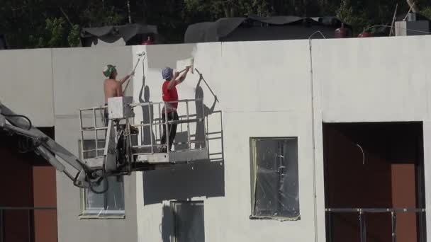 Εργάτες-άνδρες ζωγραφίσω νέα κατασκευή σύγχρονο σπίτι τοίχο σε λευκό. 4k — Αρχείο Βίντεο
