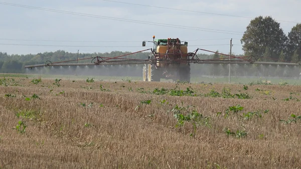 Traktor besprüht Stoppelfeld im Herbst mit Herbizidchemikalien Stockbild