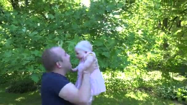 Отец с милой маленькой девочкой в солнечном парке. Вид с ручной клади. 4K — стоковое видео