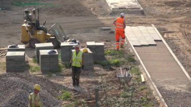 İşçi takımı kaldırıma fayanslar taşır ve serer. 4K
