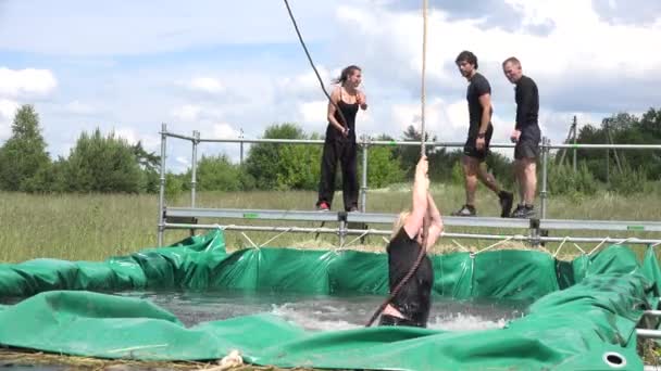 Obstáculos participantes de la carrera tratar de saltar excavado pozo lleno de agua. 4K — Vídeos de Stock
