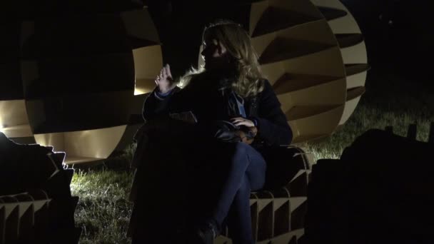 Vrouw zitten tussen karton gloeiende bal in weide 's nachts. 4K — Stockvideo