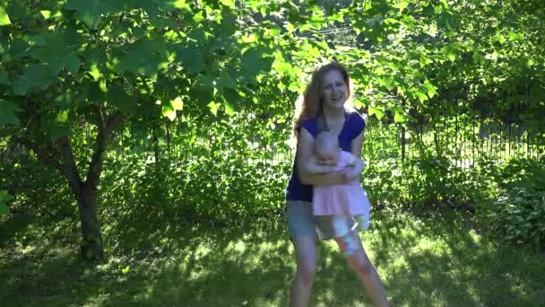 Mulher ativa com bebê filha divirta-se perto de árvore verde. 4K — Vídeo de Stock