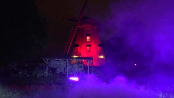 Ελαφρύ παιχνίδι και αλλαγή χρώματος στην ομίχλη στο μύλο στο πάρκο το βράδυ. 4K — Αρχείο Βίντεο