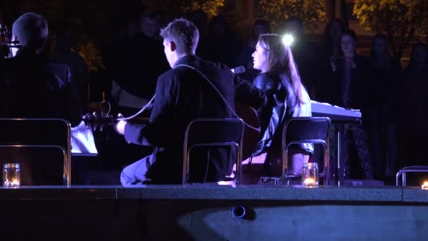 Vista posteriore cantare suonare banda musicale nel centro della città in serata. 4K — Video Stock
