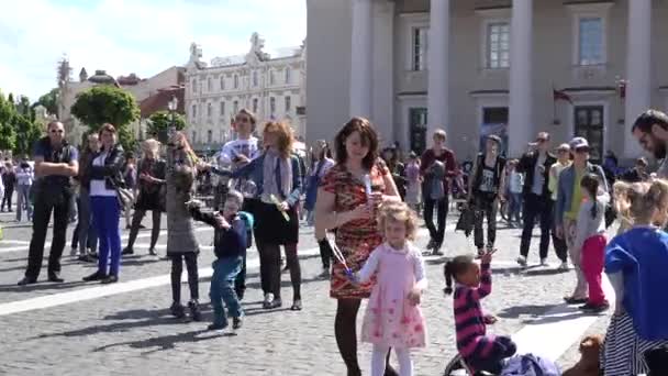 Веселые люди наслаждаются пузырчатым ударом на главной площади Вильнюса. 4K — стоковое видео