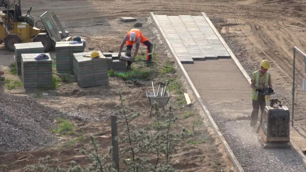 Bauarbeiter legen Steinplatten in Sand für den Weg. 4k — Stockvideo