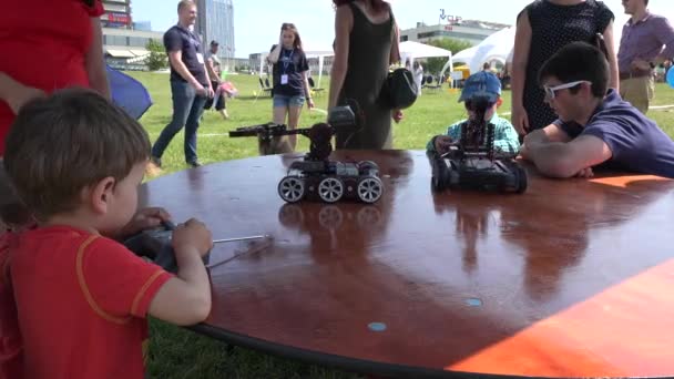 Meninos com pais controlam robôs universais modernos com controle remoto. 4K — Vídeo de Stock