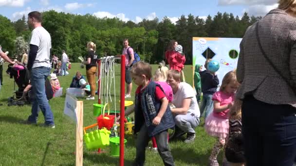 Jonge kinderen gooien bal in kleine speelgoedemmer hangen aan touw. 4K — Stockvideo