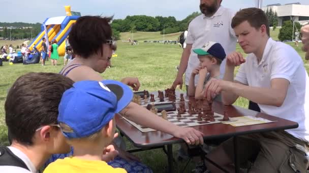 子供連れの家族は、無料屋外トーナメントでチェスをプレイします。4 k — ストック動画