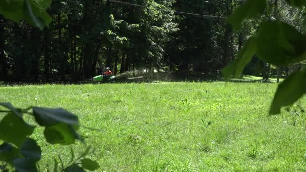 Trabajador paseo cortacésped tractor y pareja joven en el parque. 4K — Vídeos de Stock