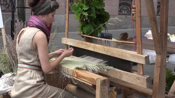 Ragazza tessere tappeto di erba piegata con vecchio telaio vintage all'aperto. 4K — Video Stock