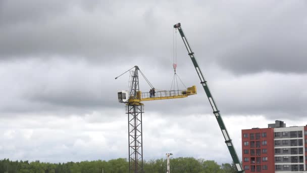 Los trabajadores desmontan la grúa sobre el fondo nublado del cielo. 4K — Vídeos de Stock