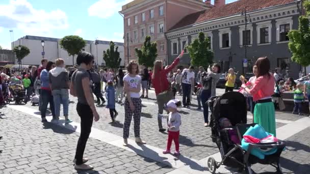 Personas felices disfrutan de golpe de burbuja en la plaza principal de Vilna. 4K — Vídeo de stock