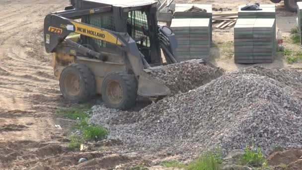Escombros especiales de carga de tractor en cuchara cerca de baldosas de la acera pila. 4K — Vídeo de stock