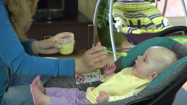 Moeder en baby in autostoel eten plantaardige PAP. . 4k — Stockvideo