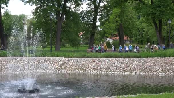 Εκδρομή για παιδιά με δάσκαλο σε καταπράσινο πάρκο με σιντριβάνι. 4K — Αρχείο Βίντεο