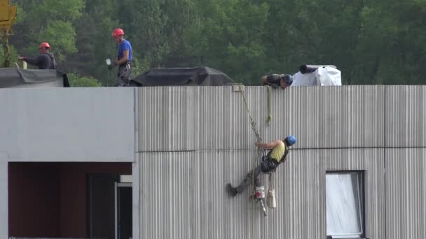 Trabalhador de escalonador alto trabalha na parede da casa pendurada na corda. 4K — Vídeo de Stock