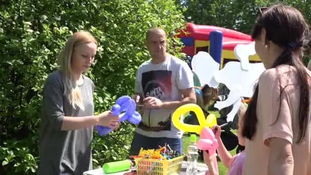 Νεαρή γυναίκα χτύπημα και συστροφή μπαλόνια για τη διασκέδαση των παιδιών. 4K — Αρχείο Βίντεο