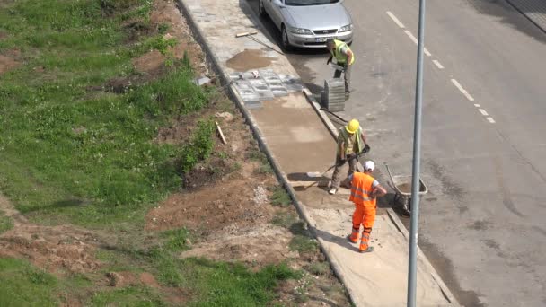 Lavoratori uomini caricare sabbia in carriola e pavimentare laici piastrelle. 4K — Video Stock