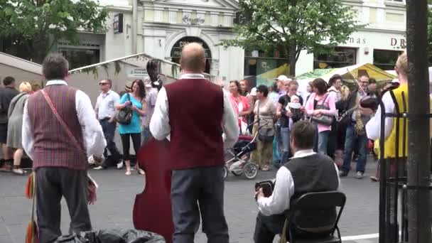 Turistas y ciudadanos disfrutan de la banda folclórica tocar música. 4K — Vídeo de stock