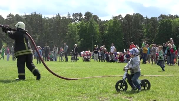 Brandweerman spray water uit slang en kinderen lopen onder waterdruppel. 4k — Stockvideo