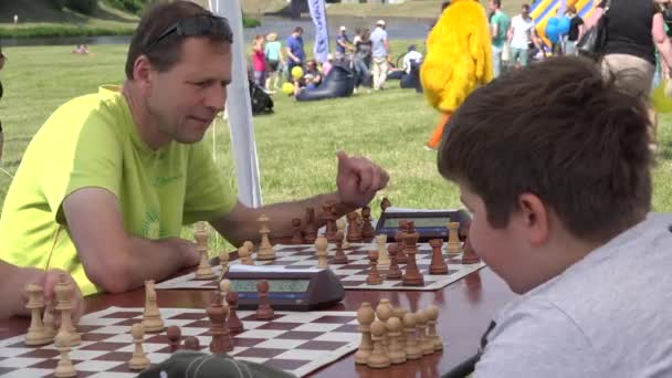 Il padre insegna al figlio a giocare a scacchi nel torneo familiare all'aperto. 4K — Video Stock