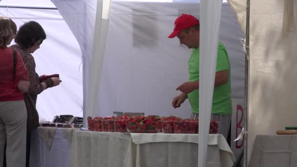 Продавец продаёт органическую клубнику на рынке. 4K — стоковое видео