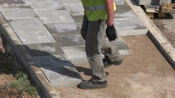 Trabajadores inmigrantes hombres pavimentar azulejos en la acera. 4K — Vídeos de Stock