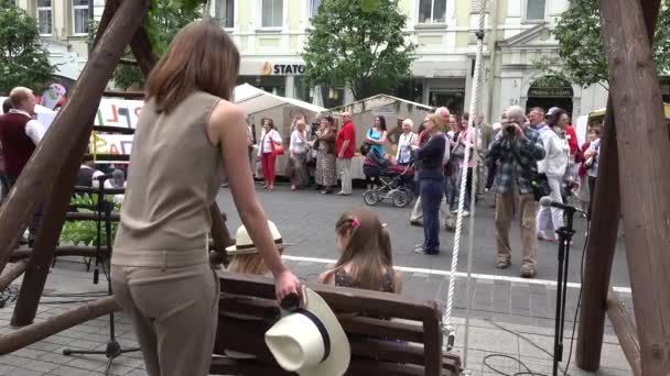 Mulheres rolar meninas no balanço e as pessoas recriar na feira ao ar livre. 4K — Vídeo de Stock