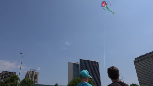 父は若い男の子に超高層ビルの間の空高く凧を飛ばすことを教える。4k — ストック動画