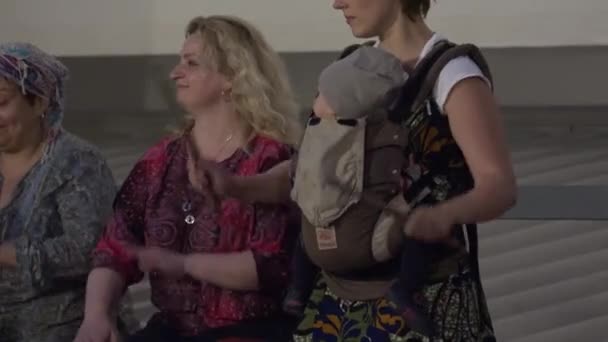 Taşıyıcıda bebeği olan kadın ve davulcu takımı davulla müzik çalıyor. 4K — Stok video