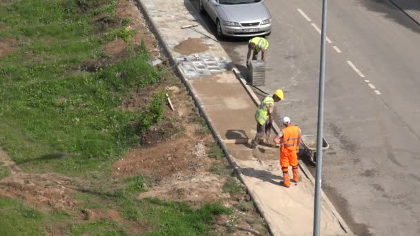 Los trabajadores cargan arena en carretilla y pavimentan las baldosas. 4K — Vídeos de Stock