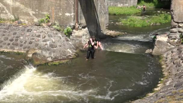 Die Teilnehmer klettern kaum durch felsigen, steinigen, schnell fließenden Fluss. 4k — Stockvideo